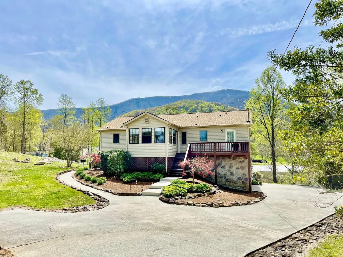 This image features the house with a welcoming porch set against a backdrop of landscaped gardens and mountains. The porch, expansive lawn, and distant peaks create an inviting setting for outdoor group activities, barbecues, and enjoying the natural surroundings together.