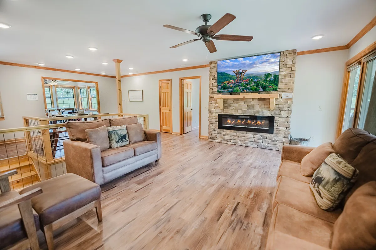 A welcoming living area with comfortable seating, rich wood accents, a warm fireplace, and a television. The room is designed for relaxation, connection, and sharing stories, providing a different angle and ambiance compared to the other living room image.