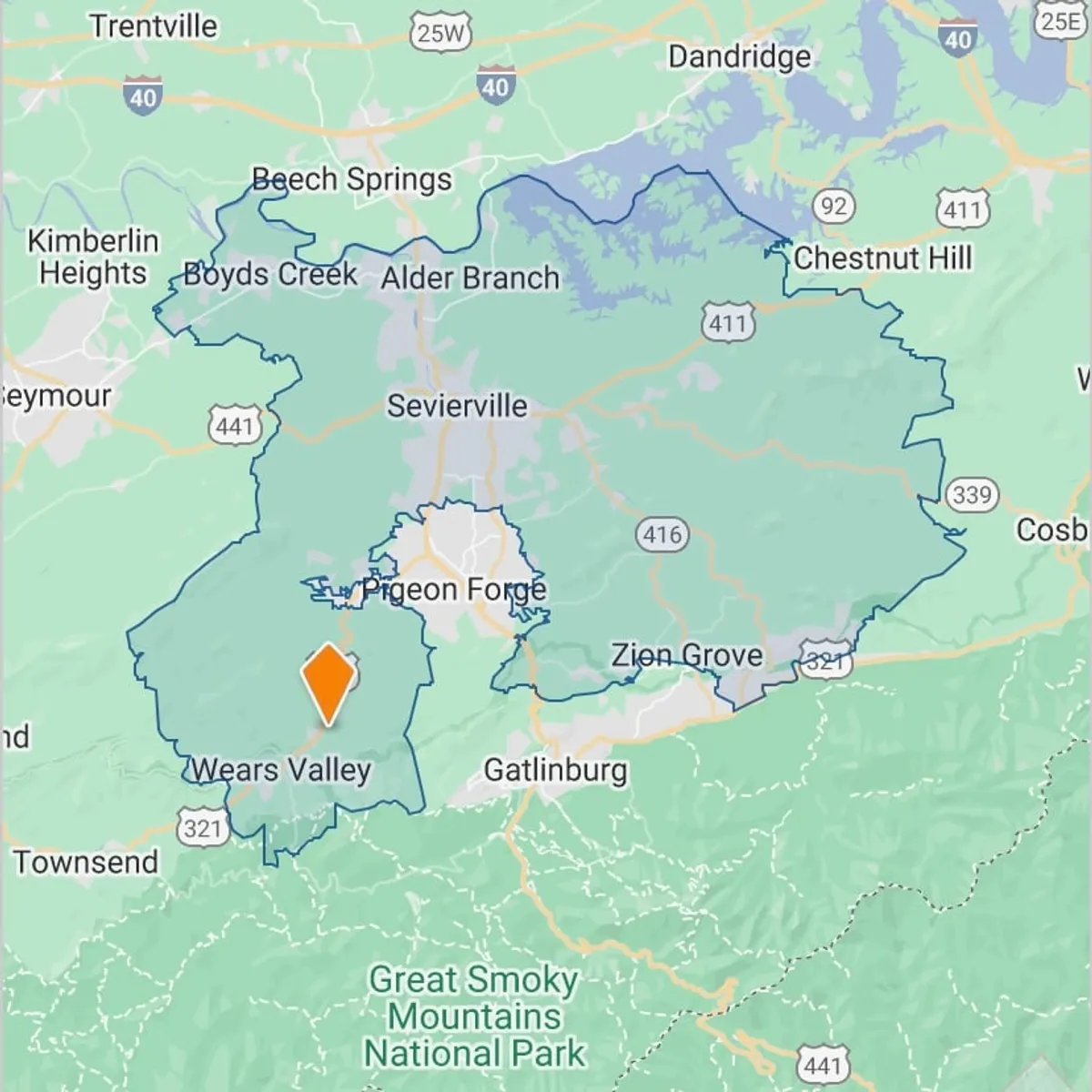 A sweeping view over the Great Smoky Mountains, capturing Wears Valley, Pigeon Forge, Gatlinburg, and the lush green ridges stretching into the distance. The landscape is framed by vibrant trees, evoking a sense of outdoor adventure and natural beauty.