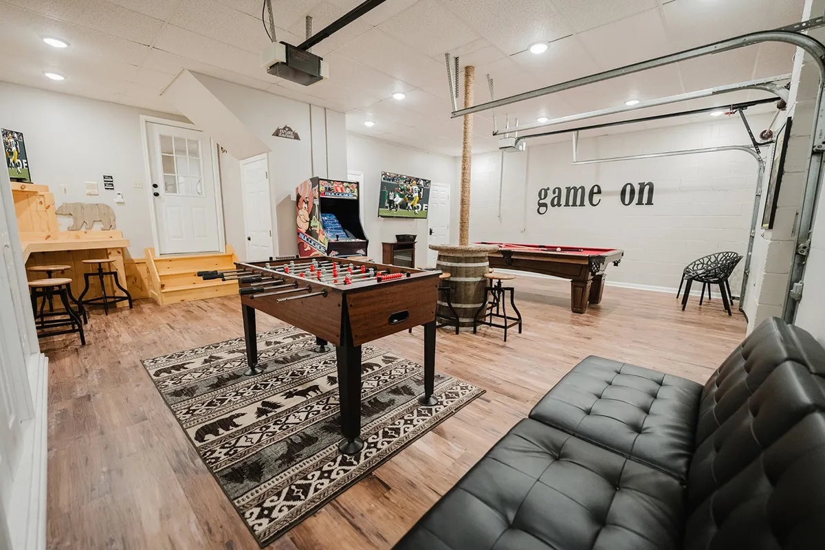 A vibrant game room scene featuring a foosball table, pool table, arcade game, and comfortable seating. The space exudes energy, with pops of color and diverse activity zones for friendly competition and group fun.